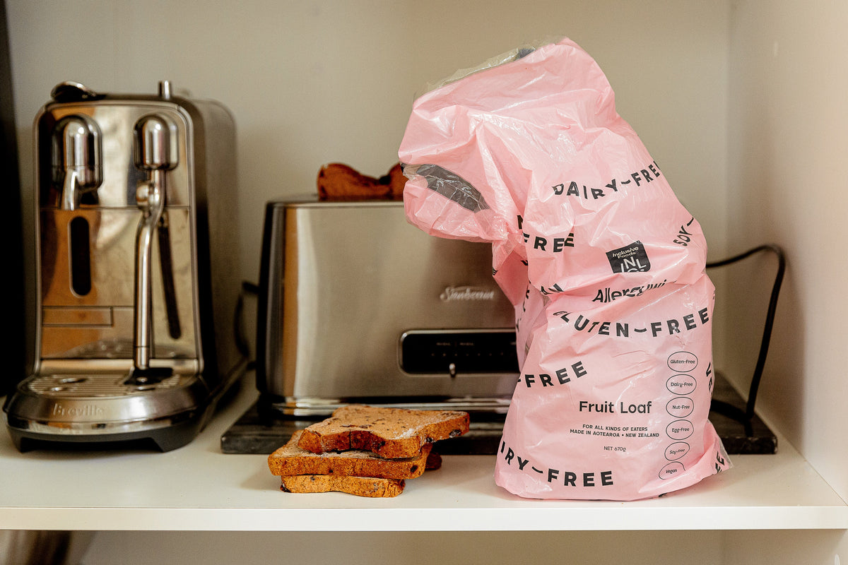 A bag of fruit loaf bread next to some toast and a toaster