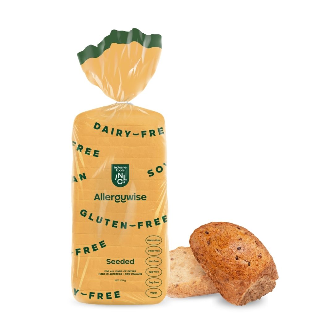 Allergywise seeded gluten-free loaf of bread next to a seeded bun on a white background.
